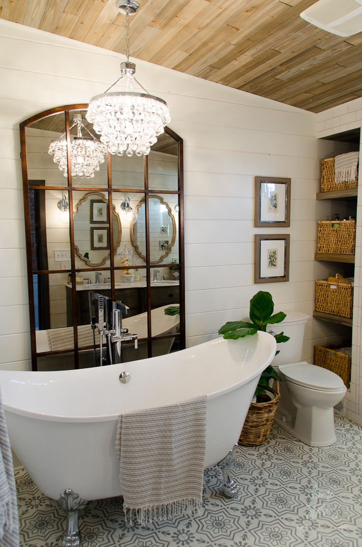 a white bath tub sitting in a bathroom next to a toilet under a chandelier