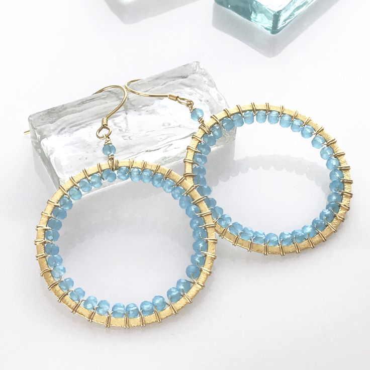 Blue Chalcedony gemstones are such a beautiful, soft shade of blue We used smooth, round stones to highlight the color 14k gold plated hoops are specifically chosen to be lightweight so you can wear them all day Perfect length for any face shape - 2.5 inches French hooks are meant to give more natural movement; safety backs added so they're worry-free Custom shapes and real gemstones make each pair one-of-a-kind We're proud that our jewelry is always handmade in the USA Whether for yourself or a Blue Wire Wrapped Round Hoop Earrings, Blue Small Hoop Earrings Wire Wrapped, Blue Small Hoop Earrings With Wire Wrapping, Blue Wire Wrapped Hoop Earrings, Blue Round Hoop Earrings For Everyday, Blue Hoop Earrings For Everyday, Handmade Blue Hoop Earrings In 14k Gold Filled, Blue Wire Wrapped Hoop Earrings For Everyday, Handmade Blue 14k Gold Filled Hoop Earrings