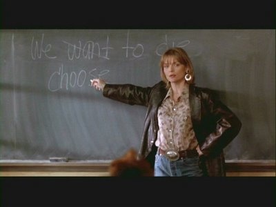 a woman standing in front of a blackboard with writing on it and pointing to the side