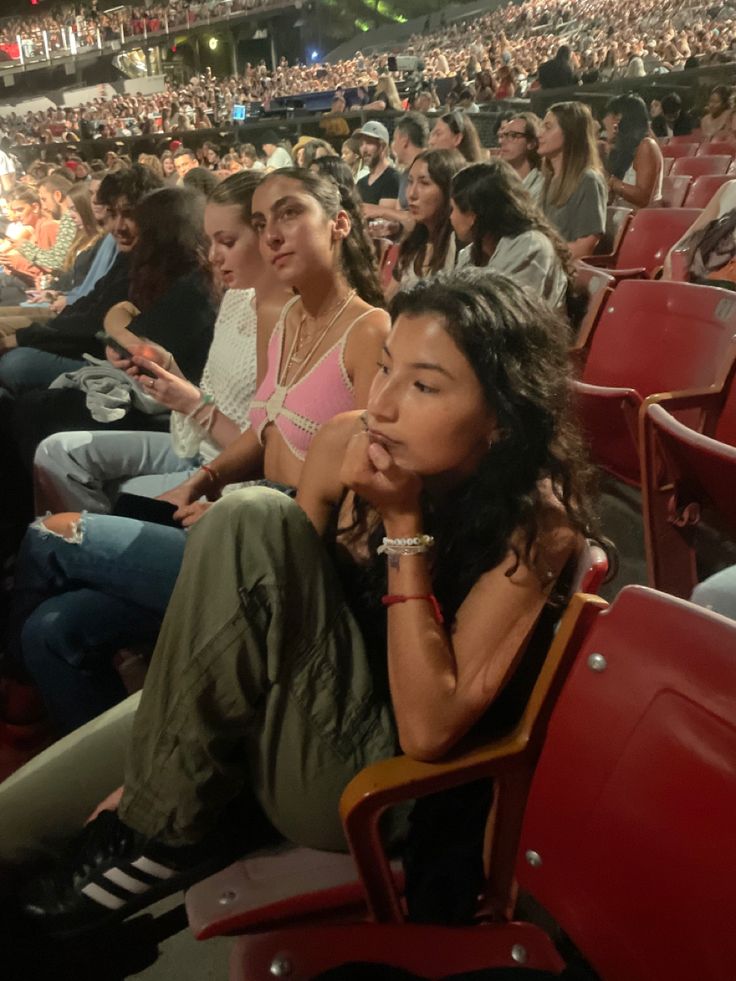 many people are sitting in the stands at a sporting event and one person is holding her chin up