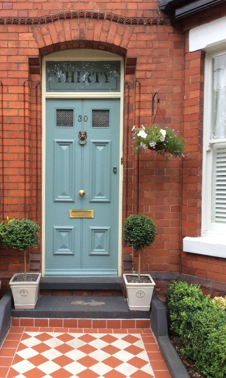 a blue front door with two planters on either side and a checkered floor