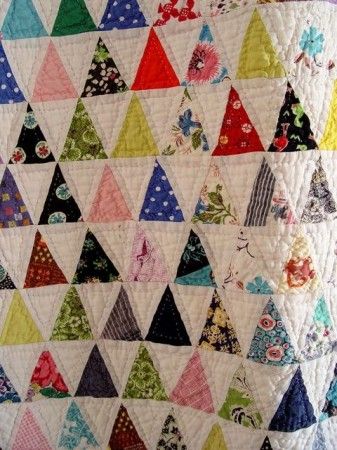 a quilted wall hanging with many different colored triangles