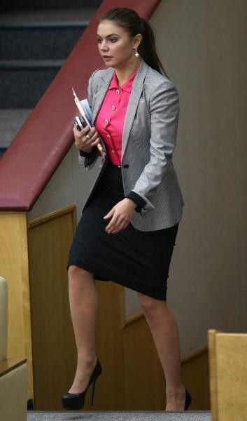 a woman in a skirt and blazer is walking down the stairs with her cell phone