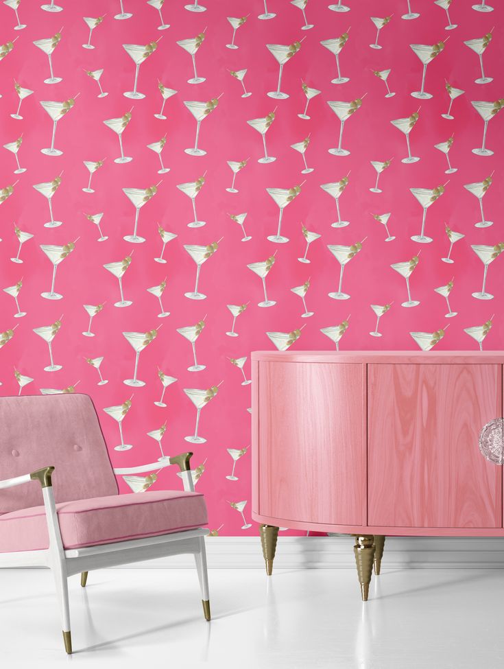 two chairs and a cabinet in front of a pink wall with martini glasses on it