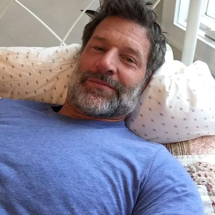 a man laying on top of a bed next to a pillow and pillows in front of him