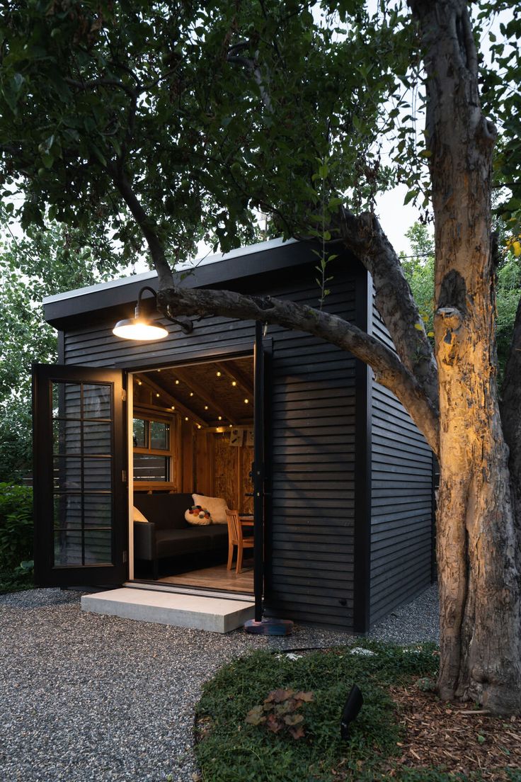 a small black shed sitting next to a tree