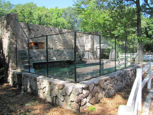 a glass enclosure in the middle of a stone wall with water flowing out of it