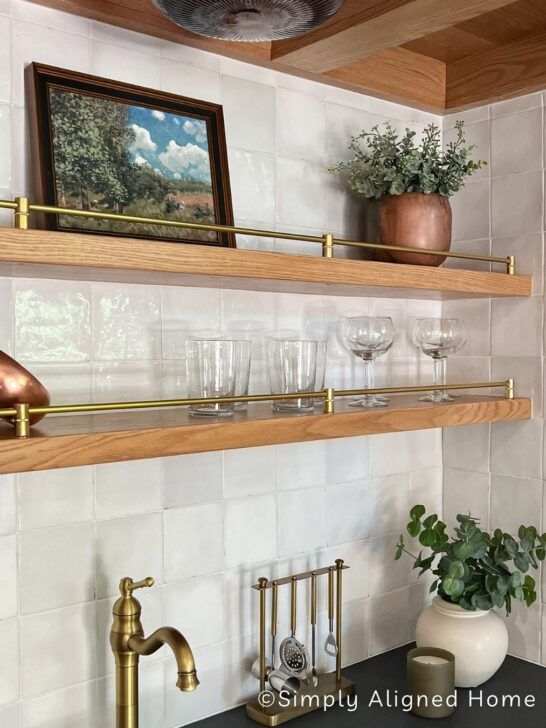 a kitchen counter topped with lots of glassware and pots on top of wooden shelves