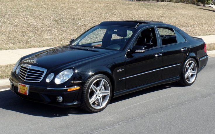 a black mercedes cls parked on the side of the road in front of some grass