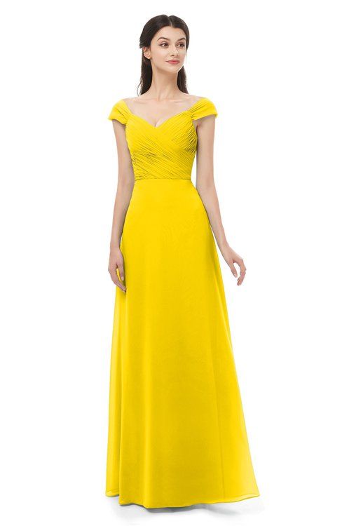 a woman in a long yellow dress standing with her hands on her hips and looking off to the side