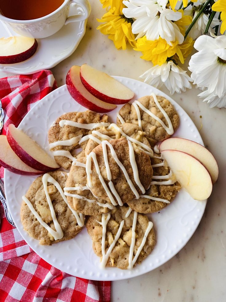 apples and cookies on a white plate with flowers in the background