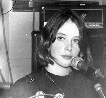 black and white photograph of a woman holding a microphone in front of a recording equipment