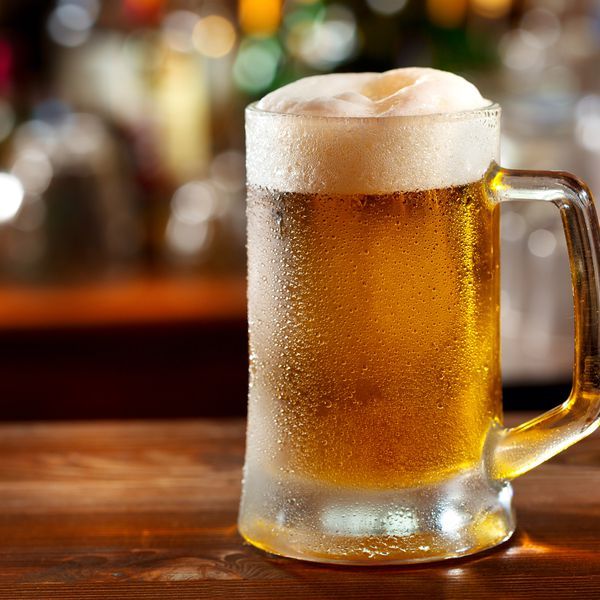 a glass of beer sitting on top of a wooden table