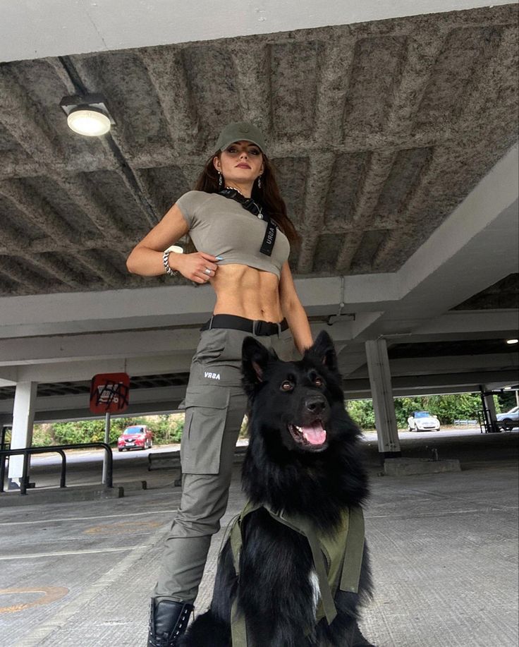 a woman standing next to a black dog in an empty parking garage with no shirt on