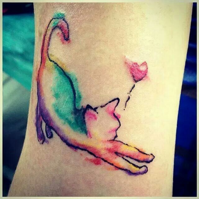 a cat tattoo on the side of a woman's leg, which is colored in pink and green