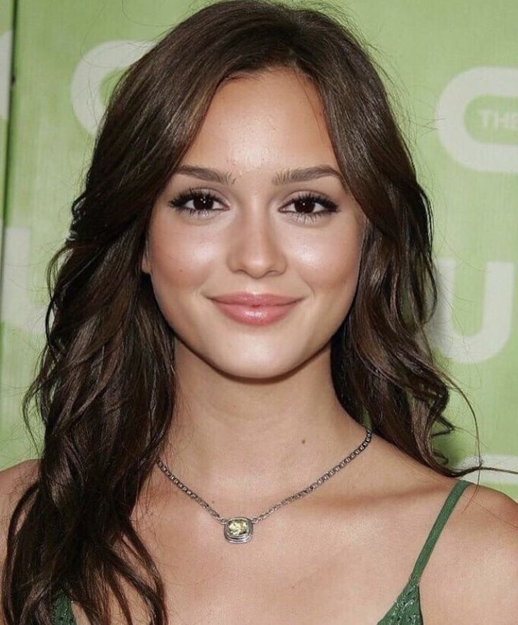 a close up of a person wearing a green dress and smiling at the camera with long hair