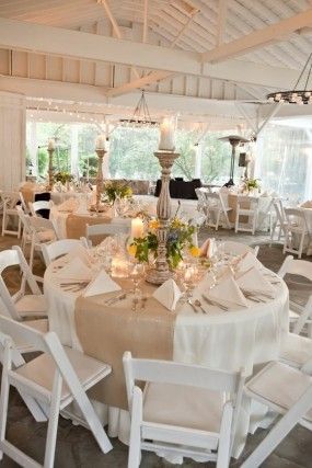 a room filled with lots of tables covered in white table cloths and centerpieces