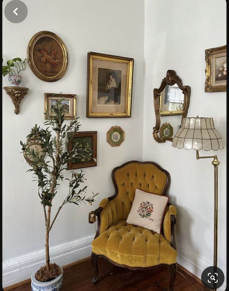 there is a chair in the corner with pictures on the wall behind it and a potted plant