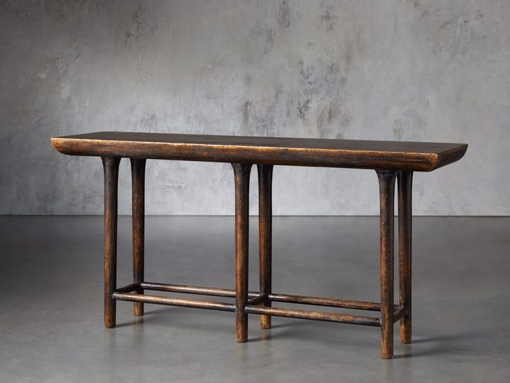 a wooden table sitting on top of a cement floor next to a wall with concrete walls behind it