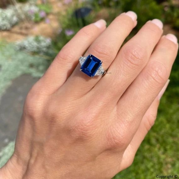 a woman's hand with a ring on it and a blue stone in the middle