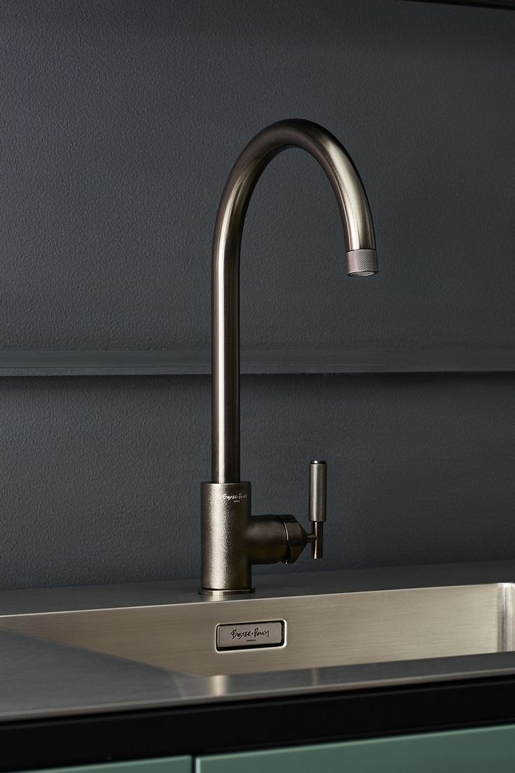 a stainless steel kitchen sink and faucet with green cabinets