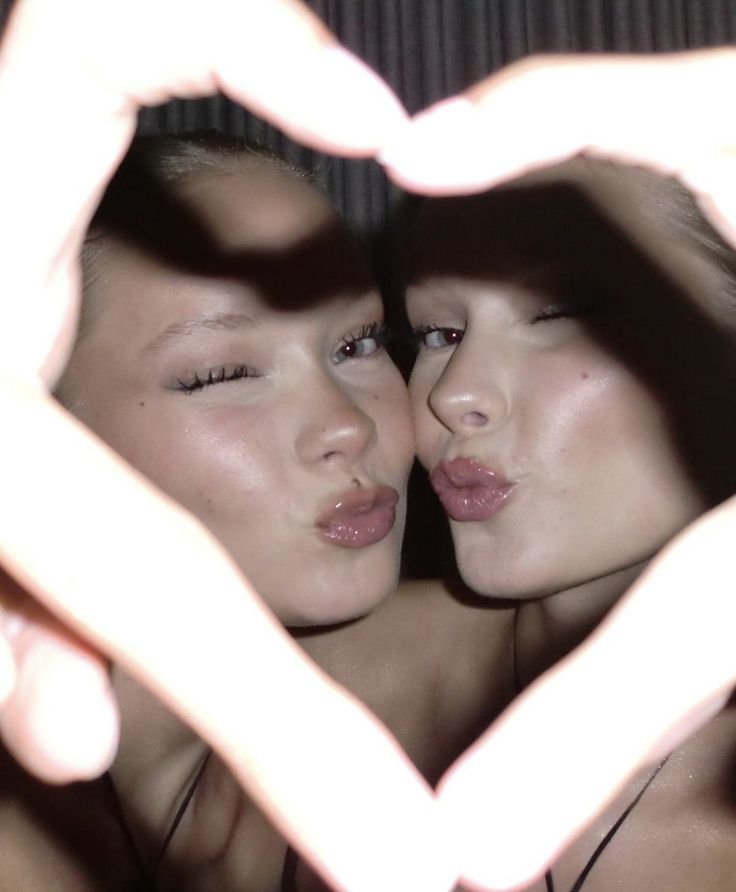 two young women making a heart shape with their hands