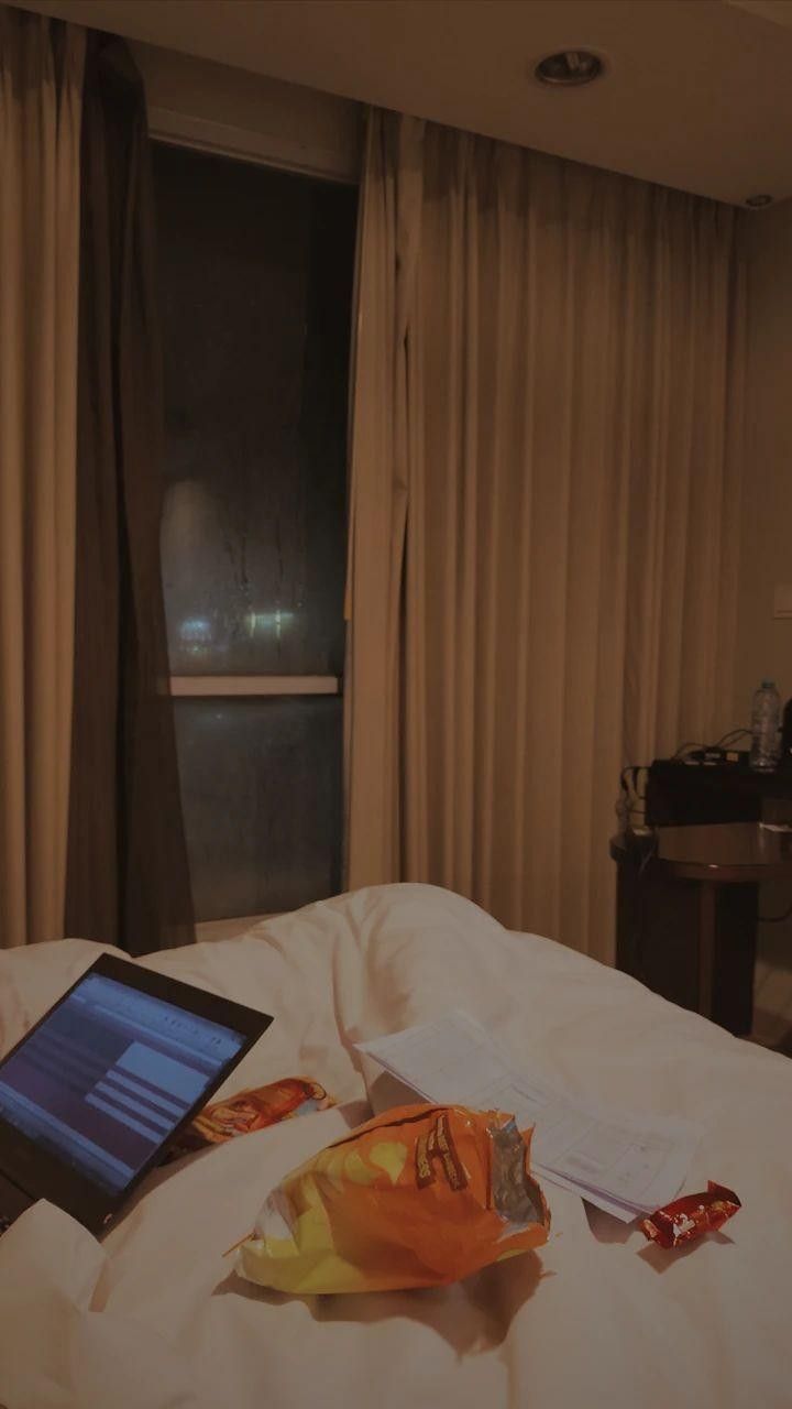 an open laptop computer sitting on top of a bed next to a bag of chips