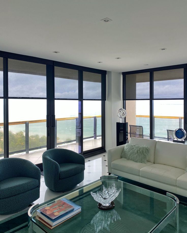 a living room filled with furniture and large windows overlooking the ocean in front of it