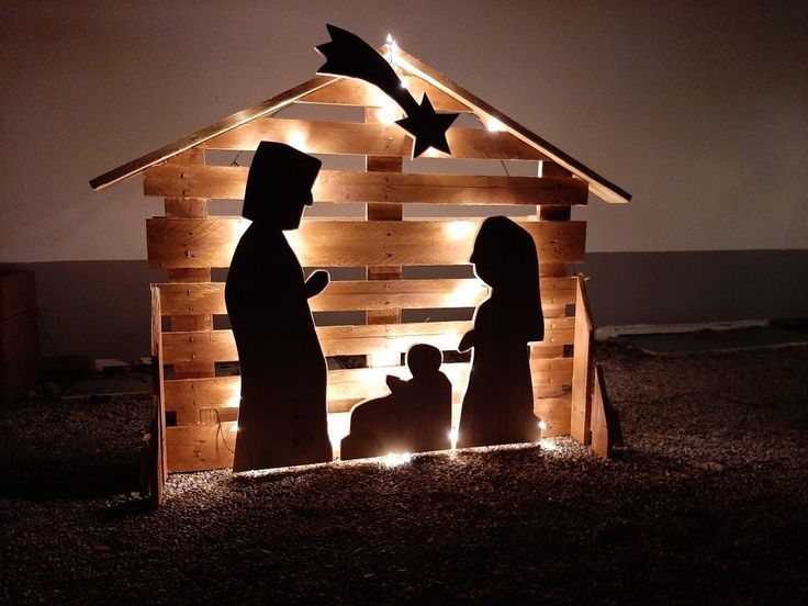 the nativity scene is made out of wood and lit up with string lights,