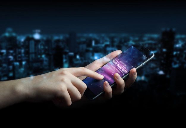 a person holding a cell phone in their hand over a cityscape at night