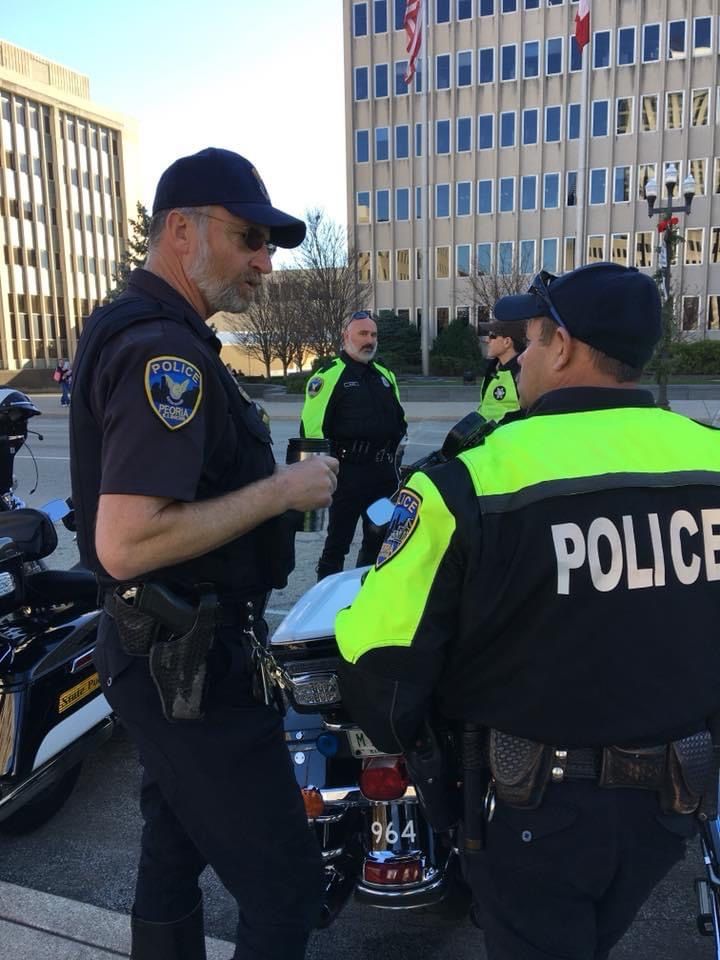 two police officers talking to each other in front of a motorcycle with another officer standing next to them