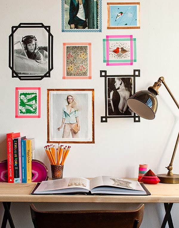 a desk with books, magazines and pictures on the wall