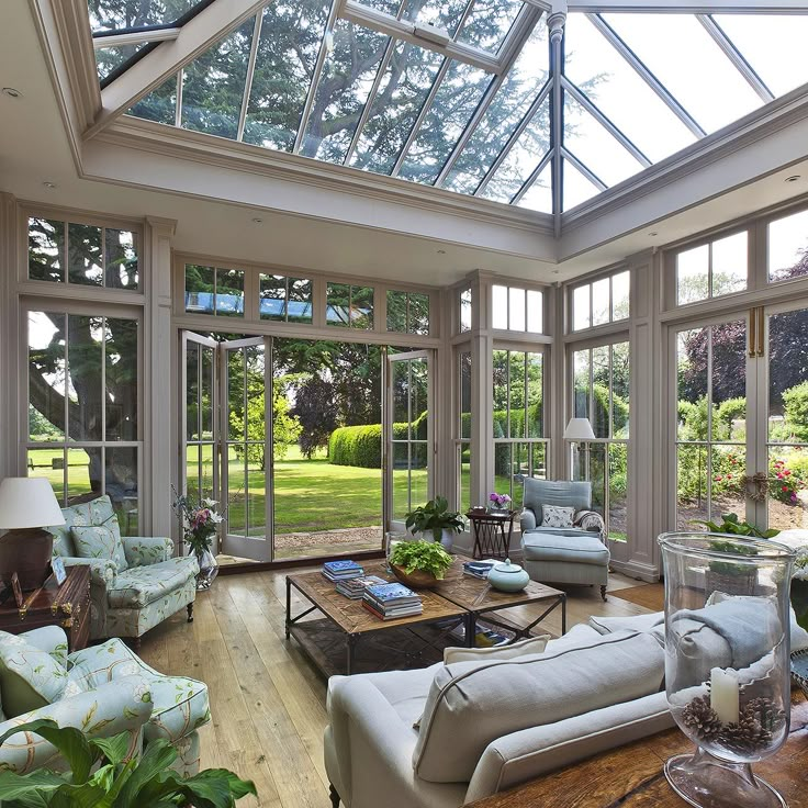 a living room filled with lots of furniture under a glass roof covered in plants and flowers