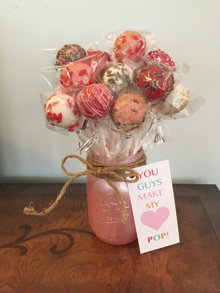 a jar filled with assorted candies sitting on top of a table next to a card