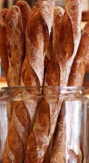 some bread sticks are in a glass jar