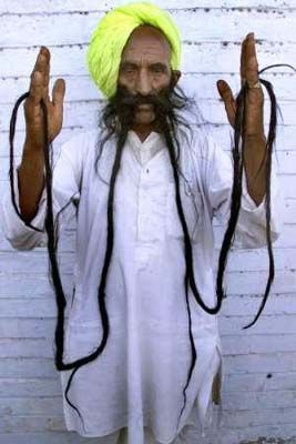 an old man with long hair and a yellow turban holding his hands in the air