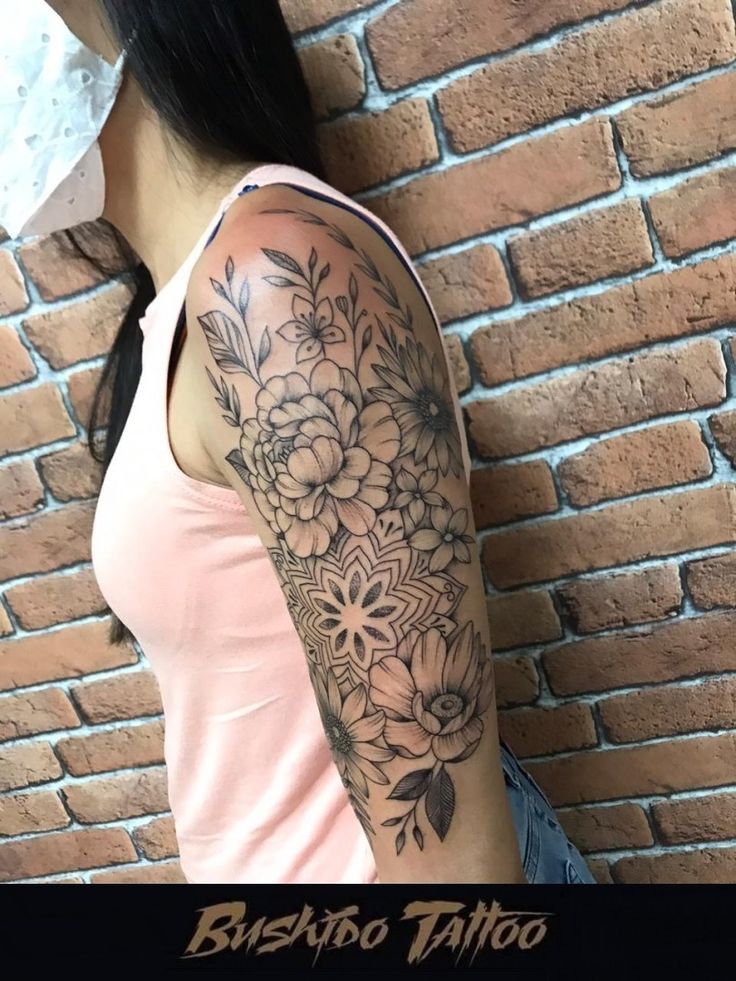 a woman with a tattoo on her arm next to a brick wall and the words bushabo tattoo