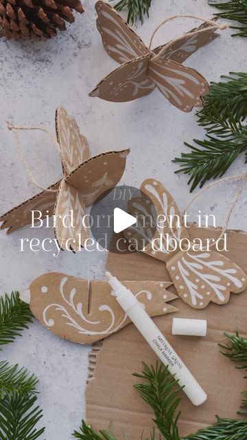 some paper butterflies are sitting on top of the snow and pine branches, with a marker in front of them