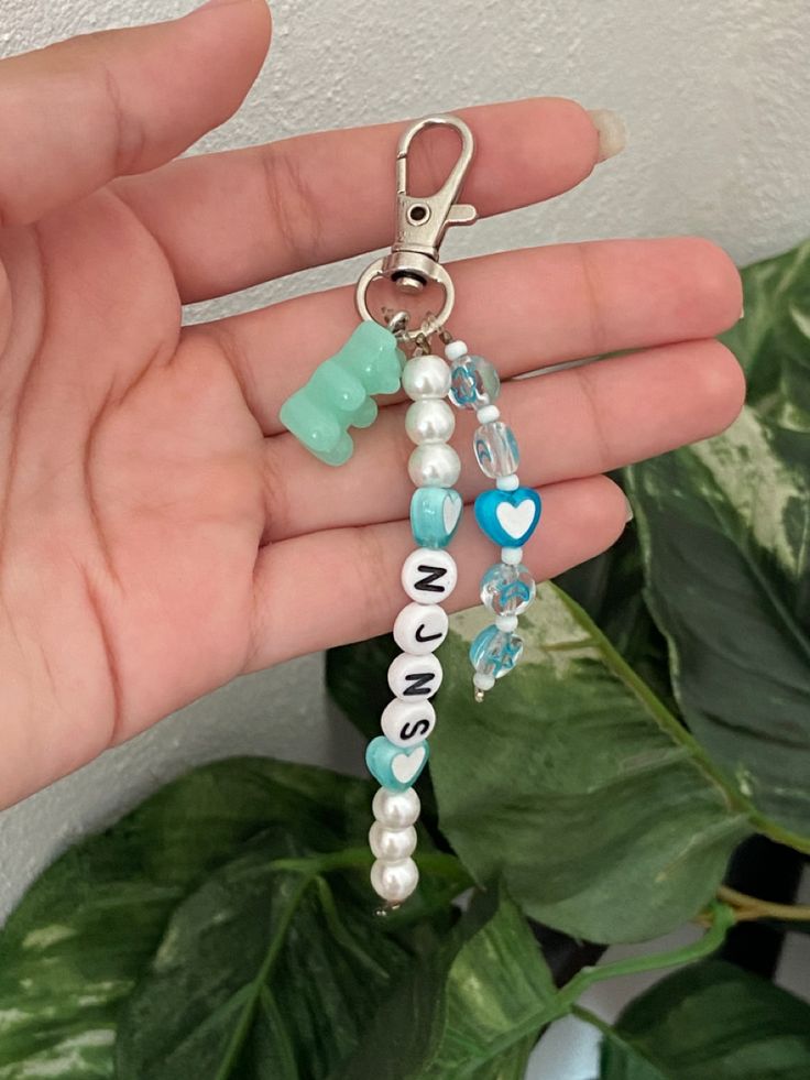 a hand holding a keychain with charms on it's side and the word love is spelled in small letters