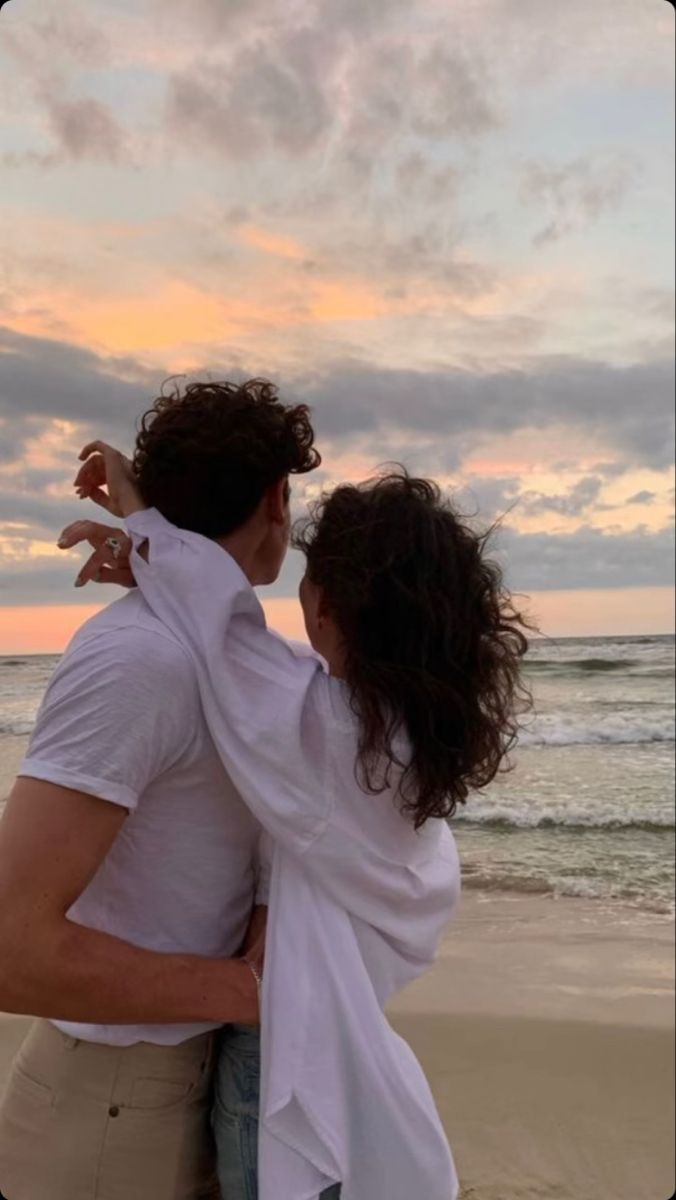 a man and woman embracing on the beach