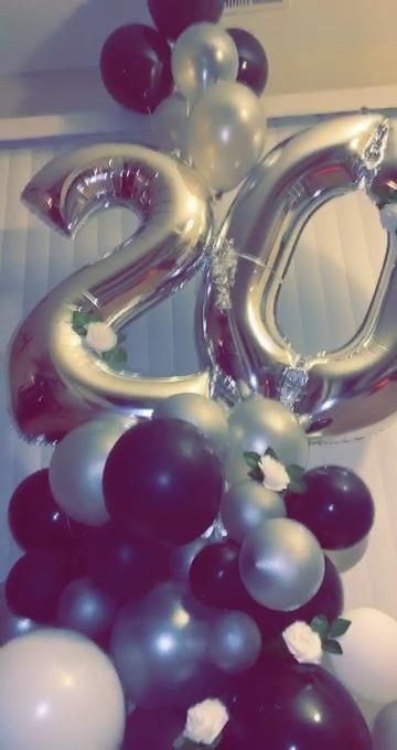 the number 20 balloon is surrounded by black, white and silver balloons that are floating in the air