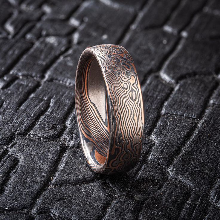 * Price may vary depending on ring size, please inquire with us directly with your needed size for accurate pricing! This beautiful Mokume Gane ring is shown in a combination of two of our other patterns, Twist and Droplet, and our Embers metal combination.  This ring is a lovely combination of rustic and elegant, with an etched and oxidized finish for a slight texture and darker look. The Embers palette features 14kt red gold, palladium and sterling silver. Design Details: Palette: Embers Patte Mokume Gane Ring, Damascus Ring, Secret Garden Wedding, Mens Rings, Dark Look, Mokume Gane, Silver Design, Men's Rings, Garden Wedding