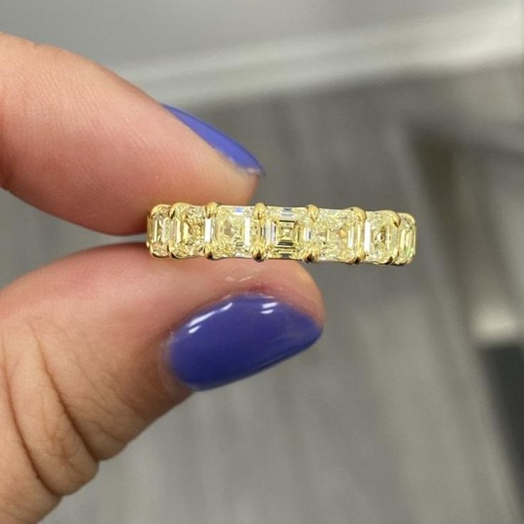 a woman's hand holding a yellow ring with three stones on the middle and one stone in the middle