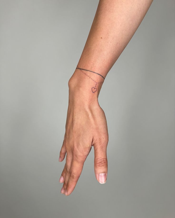 a woman's hand with a tiny heart tattoo on the middle of her wrist