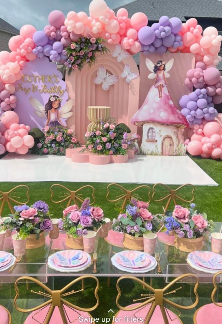 a table topped with lots of pink and purple balloons in front of a fairy castle