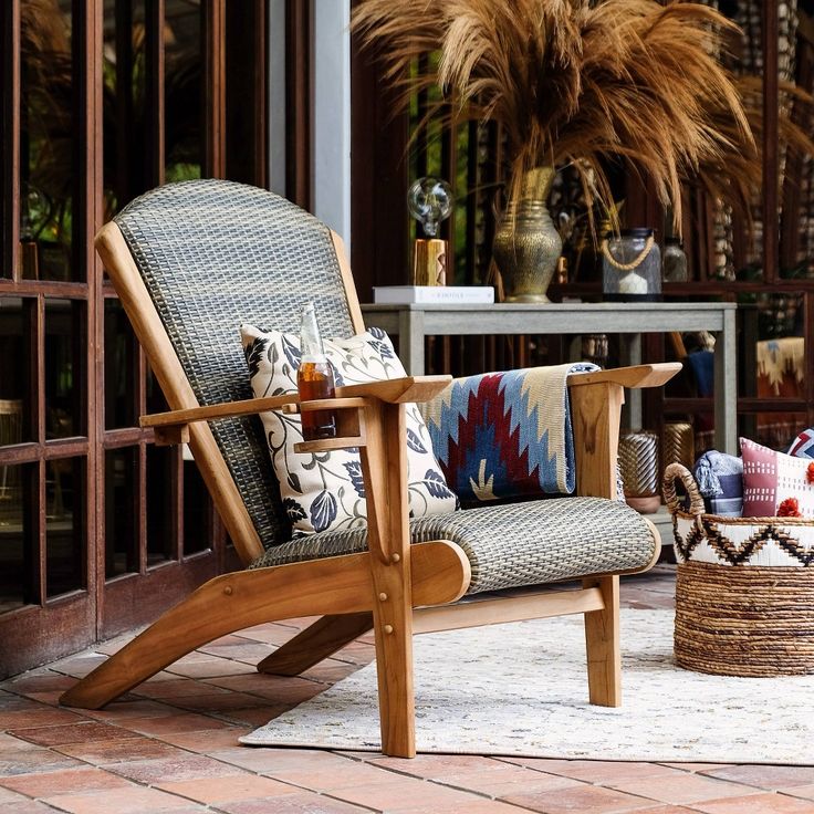 a wooden chair sitting on top of a brick floor next to a table and potted plant