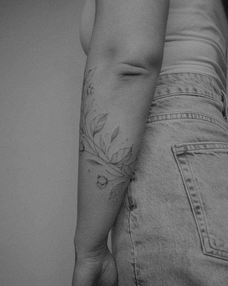 black and white photograph of a woman's lower arm with flowers on the side