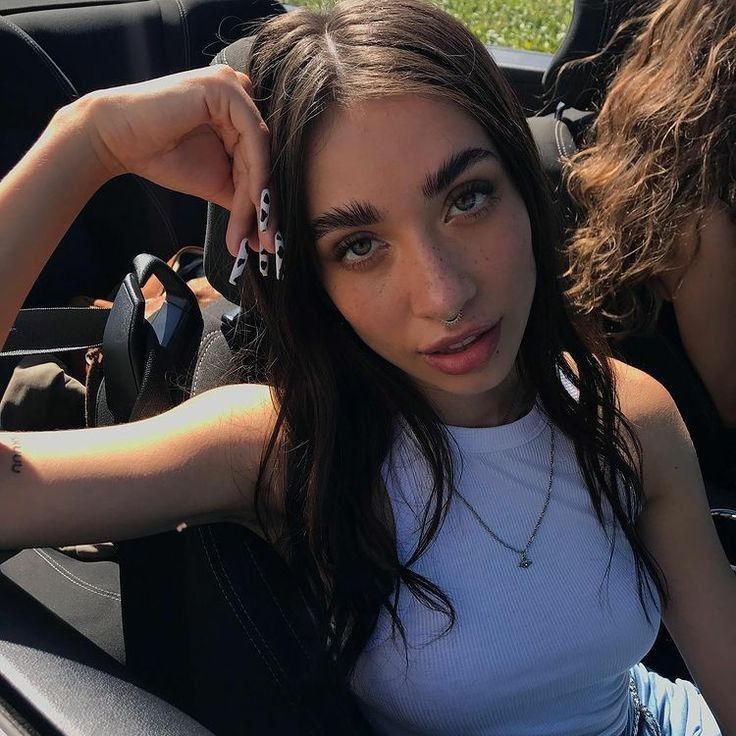 a woman sitting in the back seat of a car with her hand on her head