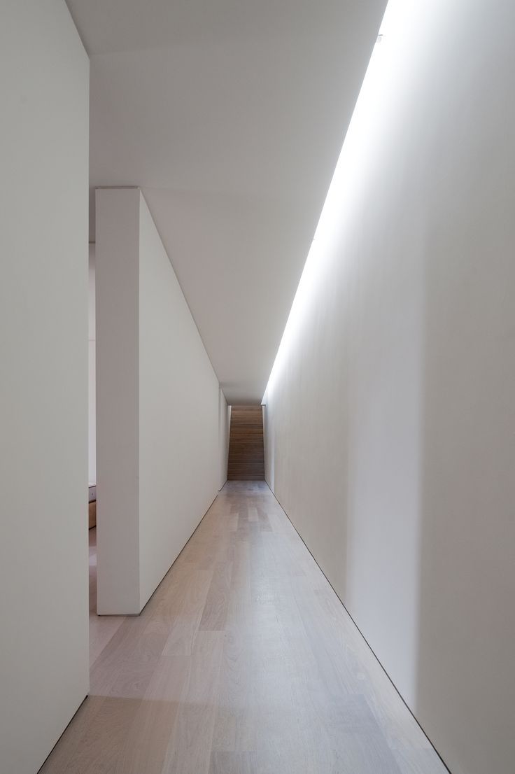 an empty hallway with white walls and wooden floors