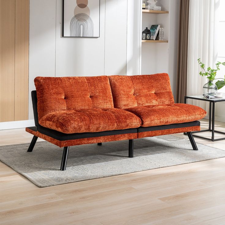 an orange couch sitting on top of a wooden floor